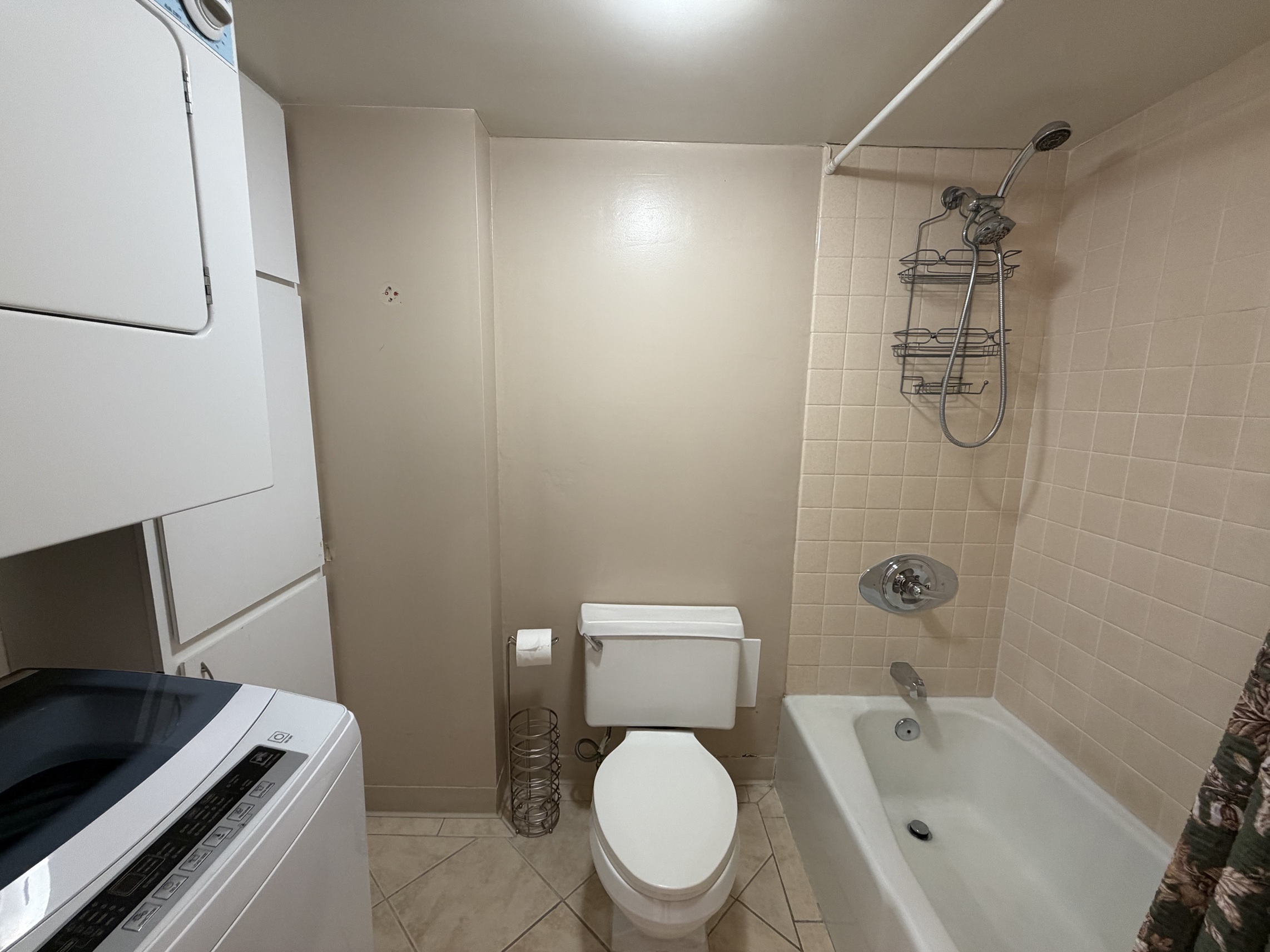 A white toilet sits next to a bathtub in a bathroom.